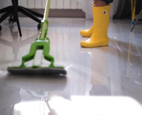 Worker cleaning up flooded water on office floor